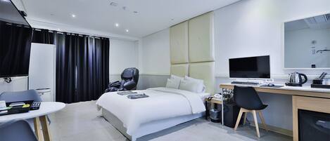 Ein modernes Hotelzimmer mit Bett, Schreibtisch, Stuhl und Fernseher.