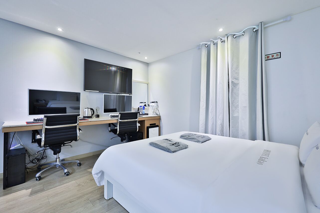 Une chambre d’hôtel moderne dotée d’un grand lit, d’un bureau avec un ordinateur, d’une télévision à écran plat et d’une machine à café.
