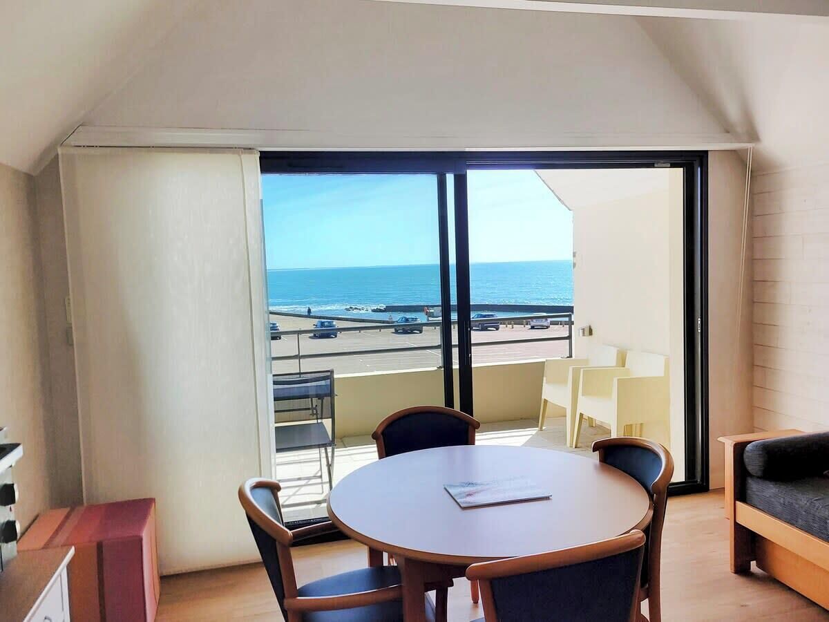 Un balcone con vista sul mare, un tavolo rotondo con sedie e un divano.