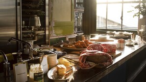 A kitchen counter with various food items, a sink, and a window with a view of a bridge. - Hotel Piet Hein Eek (Eindhoven)