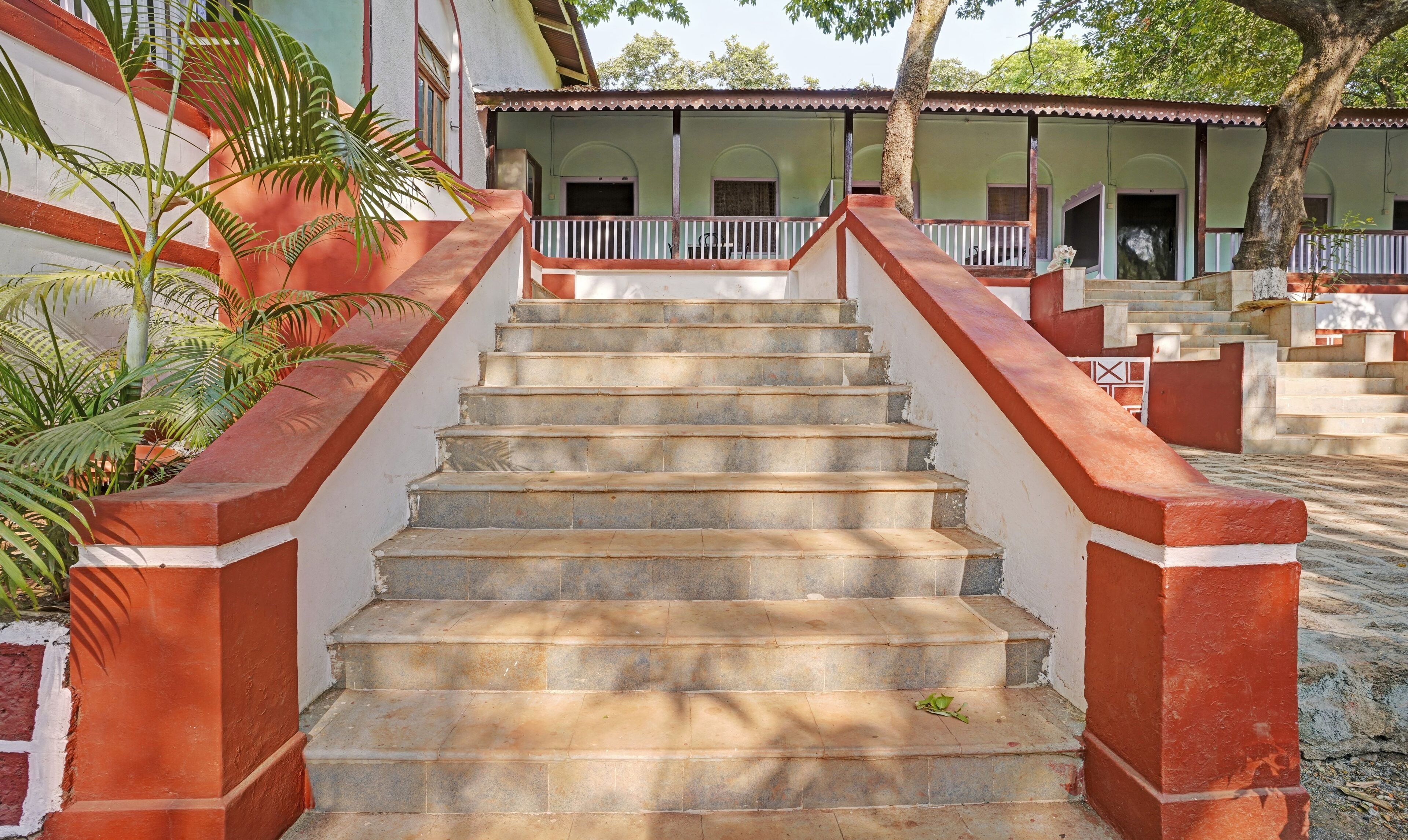 Eine Treppe aus Stein führt zu einem Gebäude mit weißer und roter Fassade.