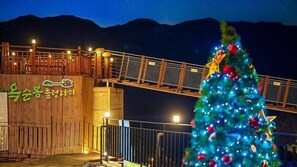 A wooden building with a sign in a foreign language, a metal bridge, and a decorated Christmas tree. - BS Jecheon Pension (Jecheon)