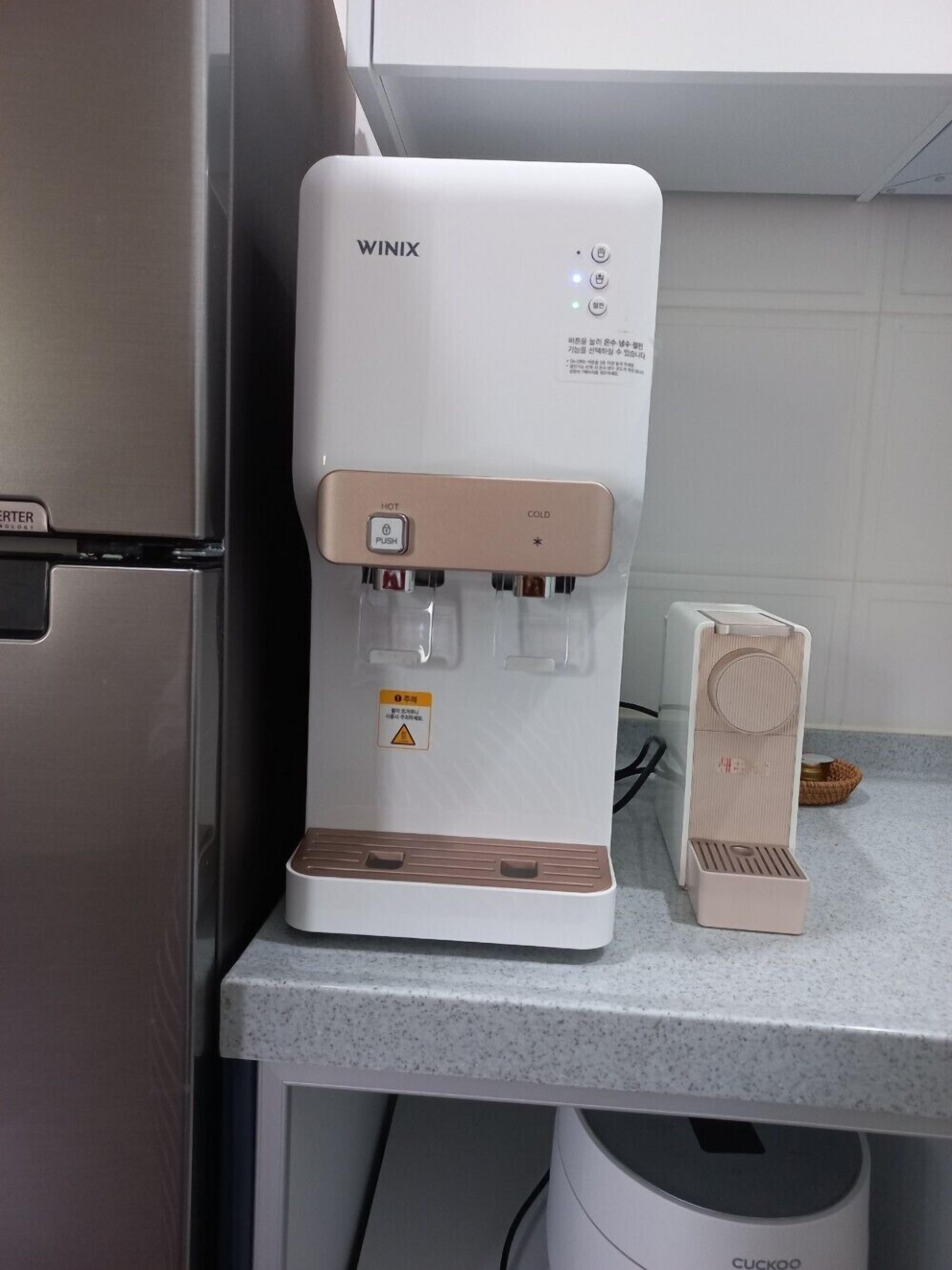 A kitchen with a white WINIX water dispenser and a Cuckoo coffee machine.