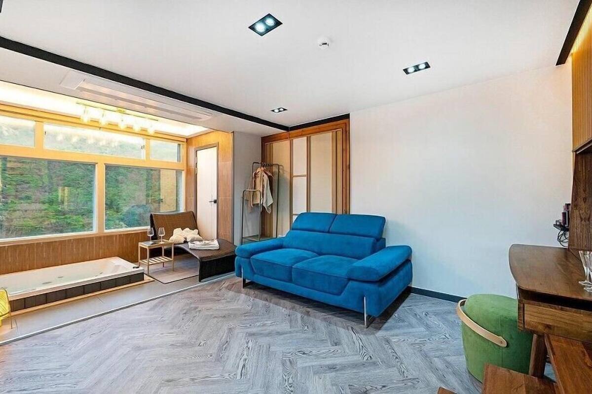 A modern room with a large window, a blue sofa, and a wooden cabinet.
