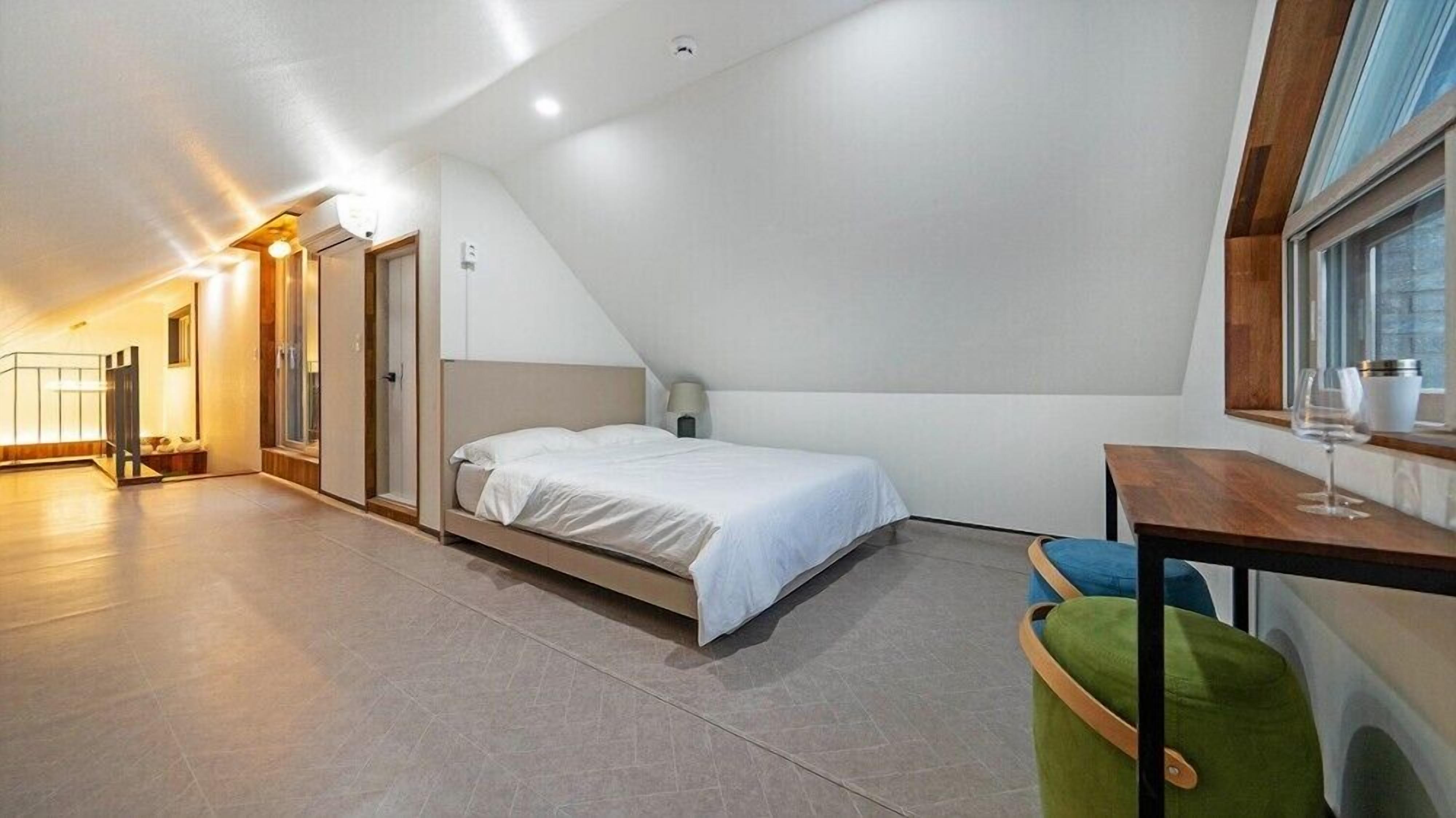 Ein modernes Schlafzimmer mit einem Bett, einem kleinen Tisch mit einem Glas und einem Fenster.