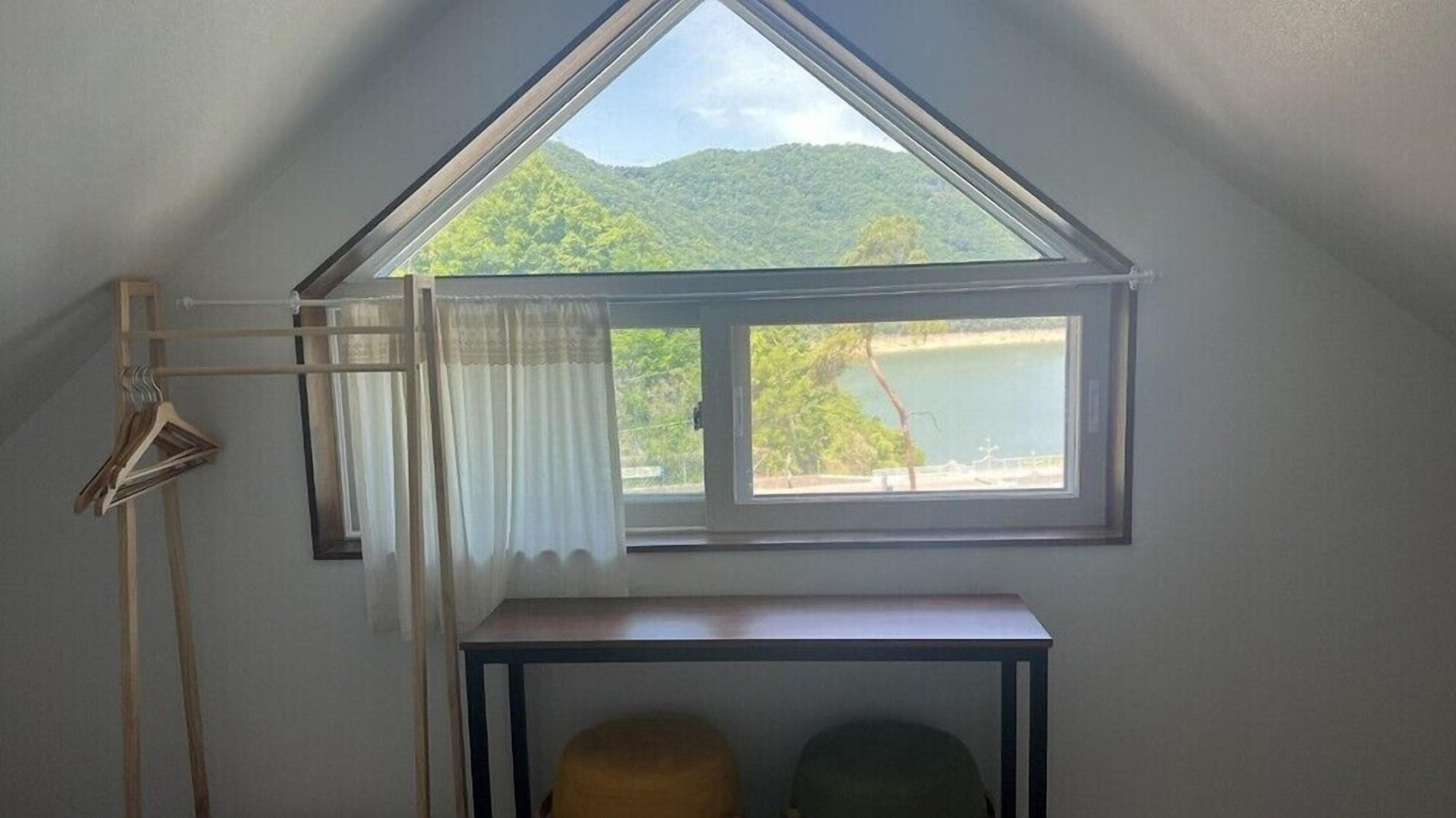 A room with a triangular skylight, a table, and a chair.
