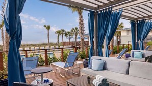 A covered outdoor seating area with a pool, lounge chairs, and a sofa.