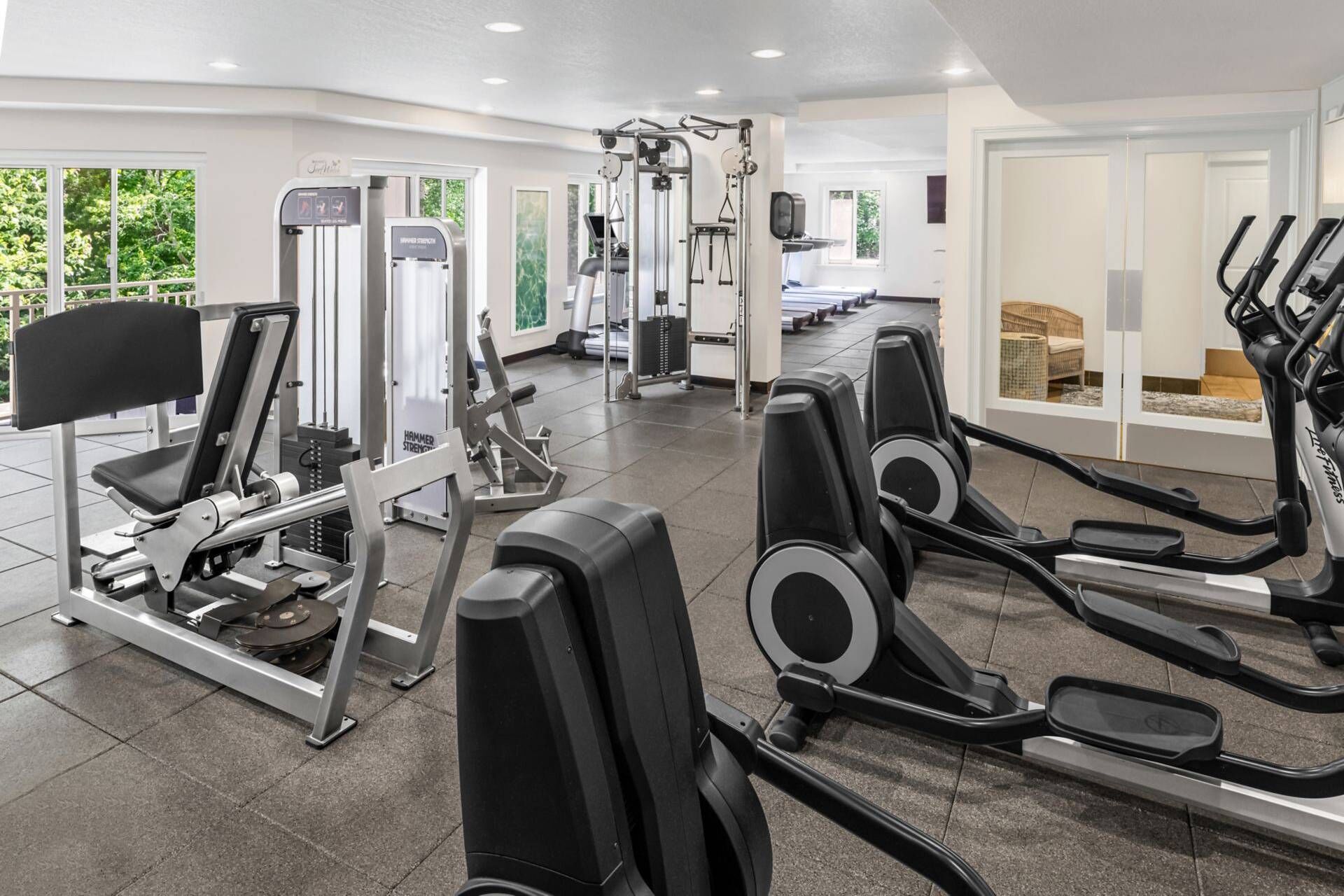 A gym with various exercise equipment including treadmills, weight machines, and a rowing machine.