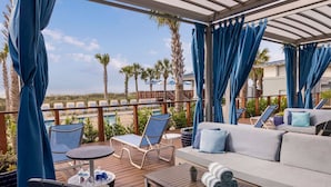 A covered outdoor seating area with a pool, lounge chairs, and a sofa. - Marriott's SurfWatch - Upscale Resort On The Beach! (Hilton Head Island)