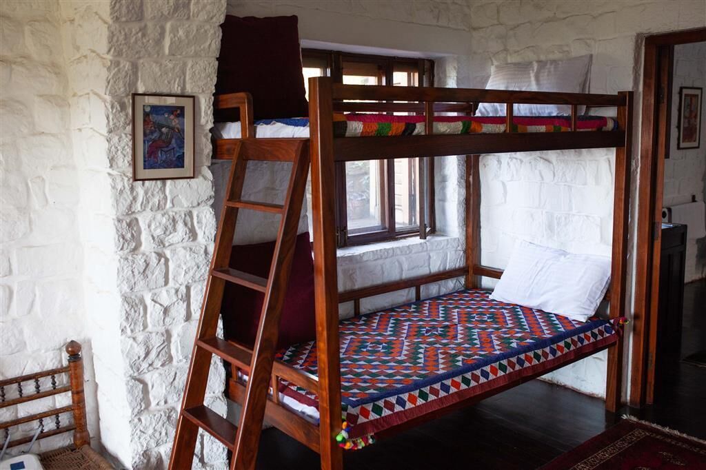 Una litera con escalera, ventana y colcha.