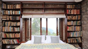 A bedroom with a large bed, multiple bookshelves, and a view through large windows. - Samarkand House (Samli)