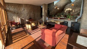 A spacious living area with a stone wall, wooden flooring, and a large red sofa. - Samarkand House (Samli)