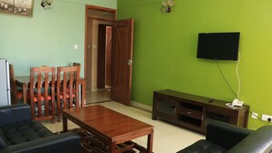 Un soggiorno con un tavolino in legno, un divano e una TV su una parete verde.