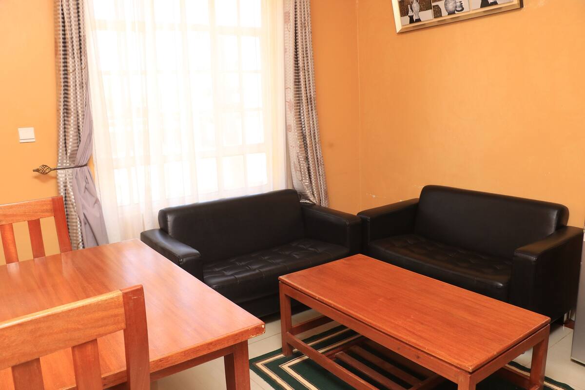 A living room with a wooden table and two black leather sofas.