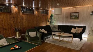 Un salon chaleureux avec une table de billard, un canapé en cuir noir et une table basse.