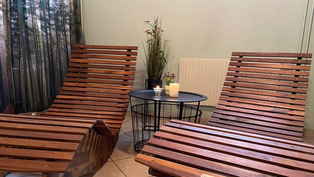 Une pièce comprenant deux fauteuils en bois et une petite table ronde sur laquelle est posée une plante en pot.