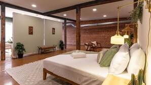 Une chambre spacieuse avec un grand lit, une table de chevet avec une lampe et une vue sur un mur en briques.
