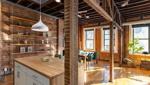 Une cuisine moderne avec des meubles en bois, un îlot central et des murs en briques apparentes.