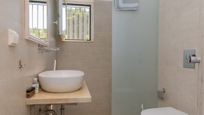 Une salle de bain moderne avec un grand lavabo blanc, des toilettes et une douche à parois de verre.