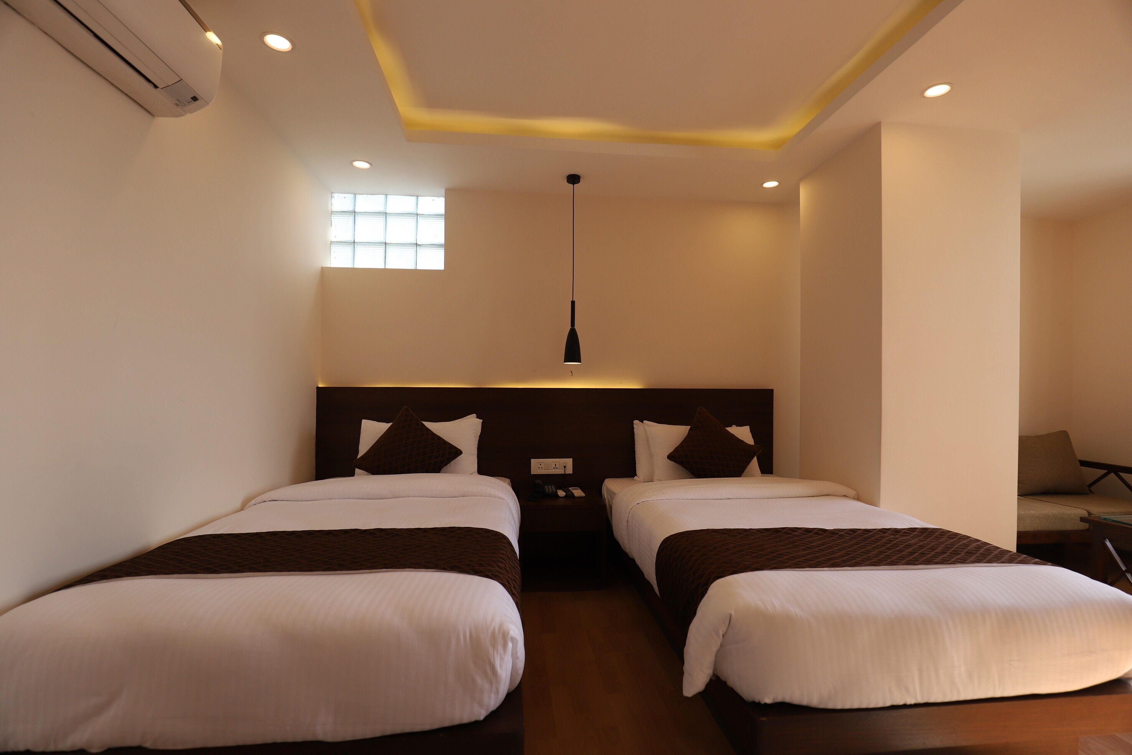 Habitación de hotel con dos camas, una mesita de noche, un escritorio y una silla.
