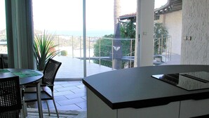 A modern kitchen with a large island, a dining area with a table and chairs, and a balcony with a view of the ocean. - Beautiful apartment near Brittany (Mandelieu-la-Napoule)