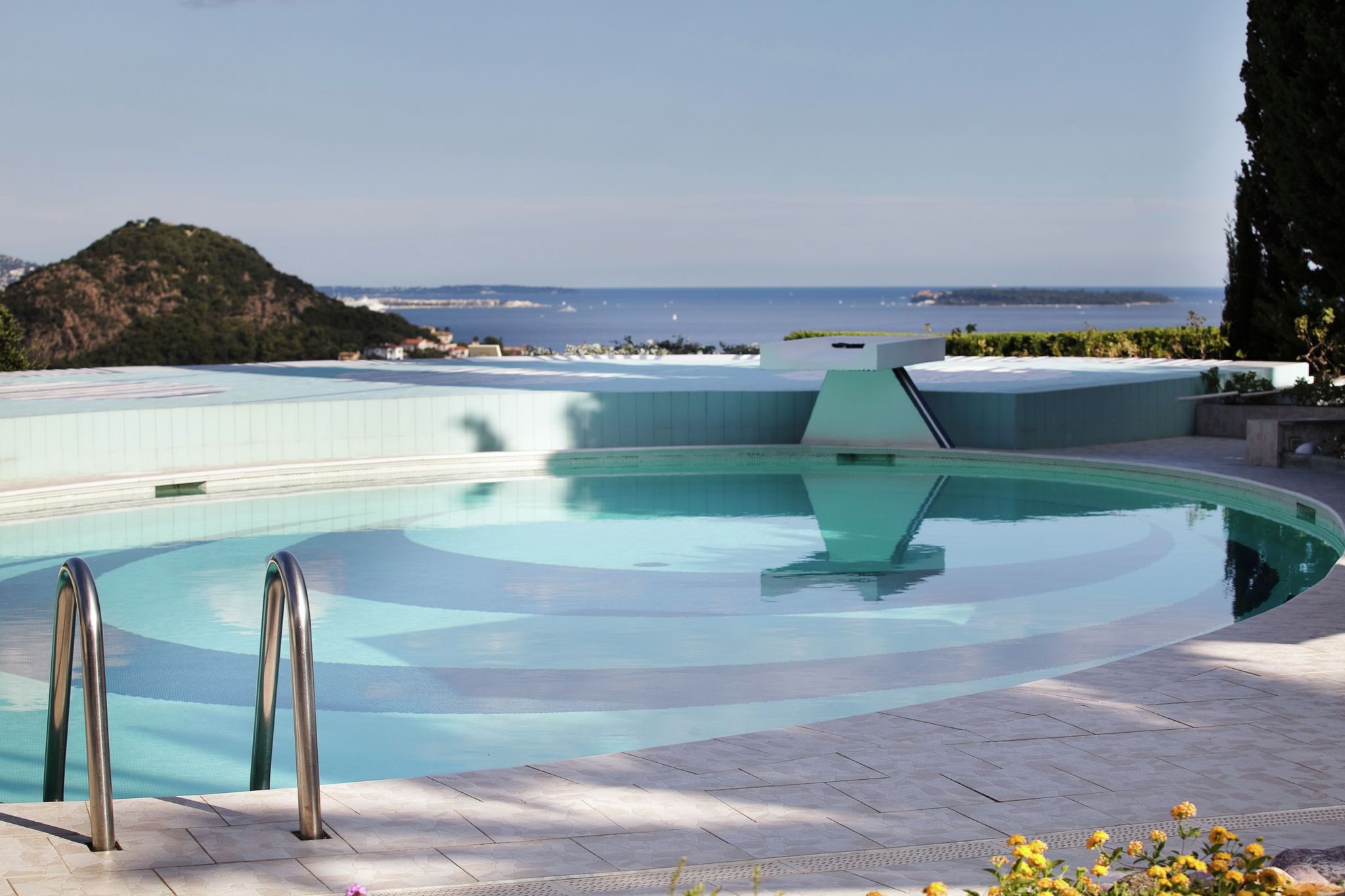 A swimming pool with a clear view of the ocean and a distant mountain.