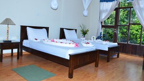 A double bed with white linens and floral decorations, a bedside table with a lamp, and a window with curtains. - Mora Heights Hotel (Arba Minch)