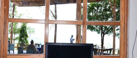 Una habitación con un amplio ventanal con vistas a una terraza con sillas y una mesa.