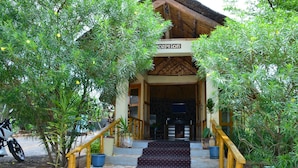 A reception area with a staircase leading up to a building entrance, surrounded by potted plants and a motorcycle parked outside. - Mora Heights Hotel (Arba Minch)