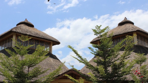 A symmetrical building with thatched roofs and wooden structures, surrounded by greenery. - Mora Heights Hotel (Arba Minch)