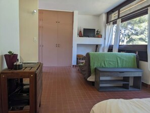 Ein Zimmer mit einem Bett, einem Fernseher, einer Couch und einem fenster mit Vorhängen.