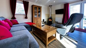A modern living room with a sofa, a wooden cabinet, a glass coffee table, and a chair. - Cherry Lodge (Godshill)