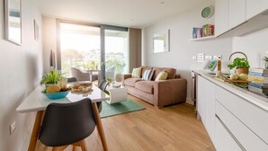 Un salon moderne comprenant un canapé, une table à manger avec des chaises et un coin cuisine avec des placards et un plan de travail.