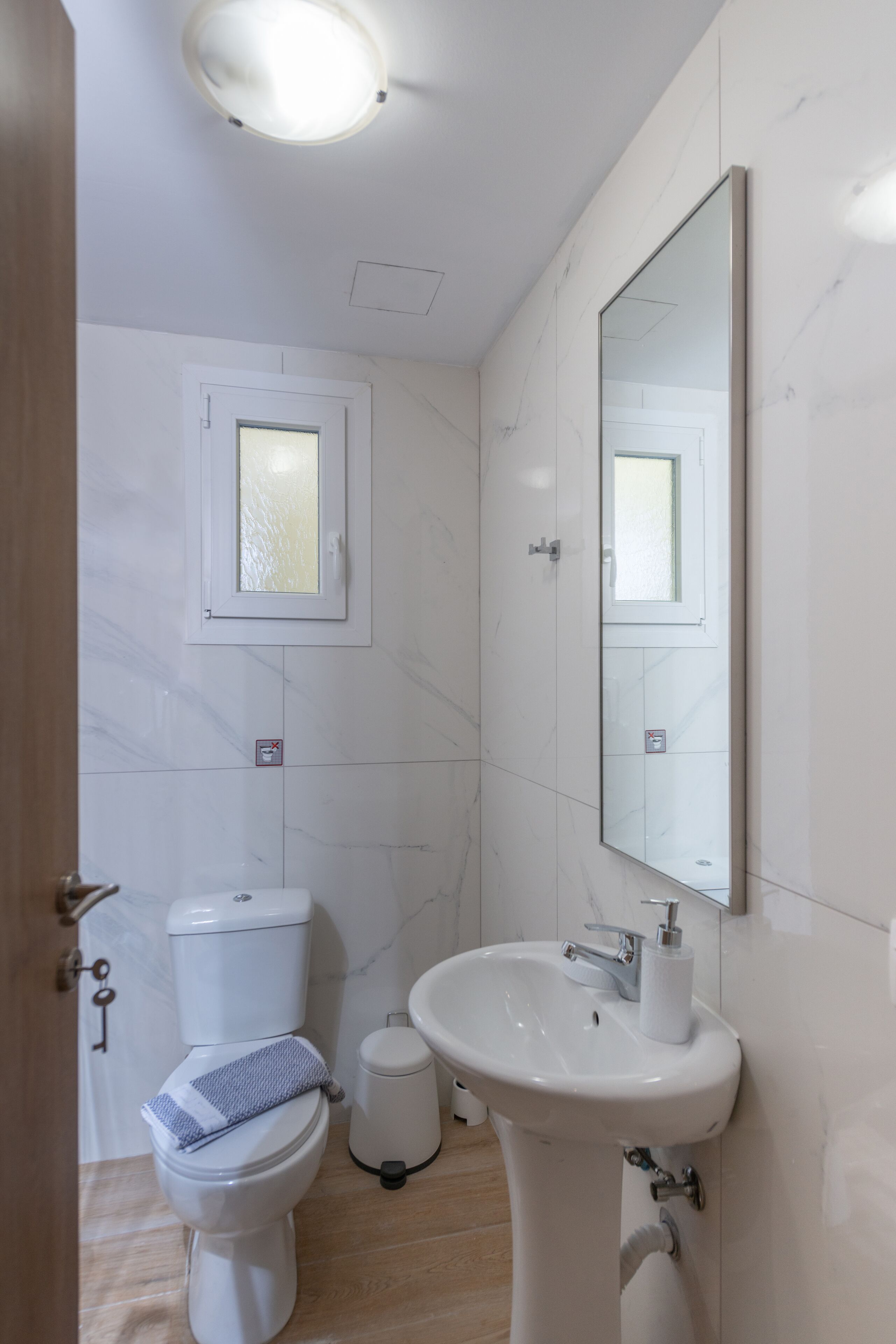 A bathroom with a toilet, sink, and mirror.