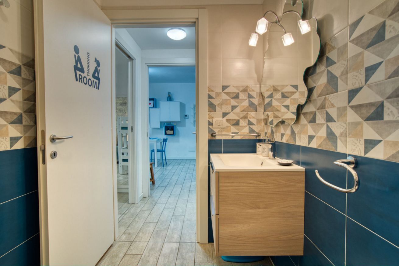 A bathroom with a geometric tile backsplash, a wooden vanity, and a door labeled 'Thinking Room.'