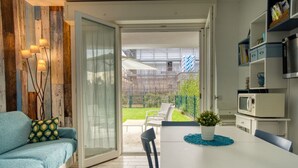 A modern kitchen with a dining area, a sofa, and a view of the backyard.