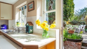 A kitchen with a wooden countertop, a sink, and a window with a view of a garden. - Bluebell Cottage - sleeps 3 guests  in 2 bedrooms (Burnham Market)