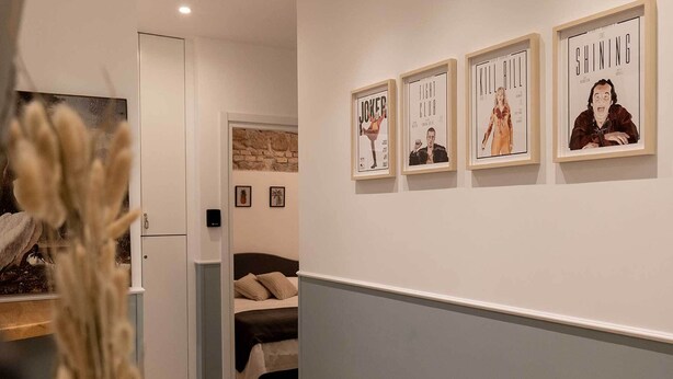 A hallway with a bed, a door, and framed movie posters on the wall. - Smart Guesthouse (Rome)