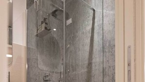 A modern shower enclosure with a glass door, a handheld showerhead, and a wall-mounted faucet. - Smart Guesthouse (Rome)