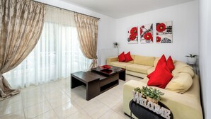 A living room with a sofa, coffee table, and artwork on the wall. - Amazing Summer Villa in Kolympia (Κολύμπια)