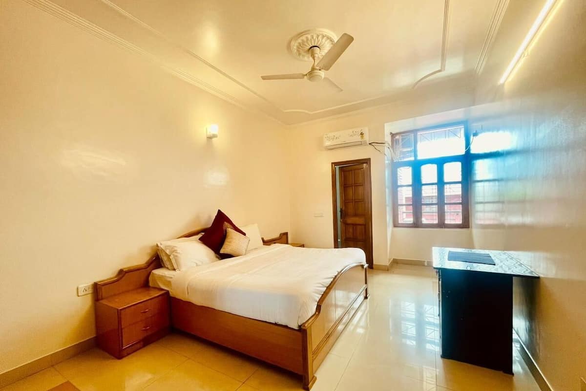 A bedroom with a bed, nightstand, desk, ceiling fan, and window with blinds.