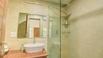 A modern bathroom with a freestanding sink, a glass shower enclosure, and a mirror above the sink.