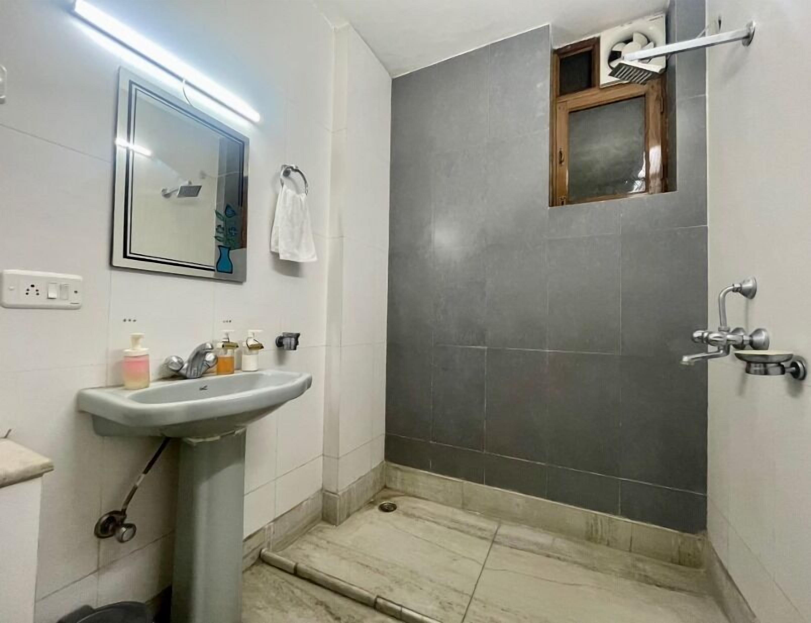 A bathroom with a sink, mirror, and shower area.