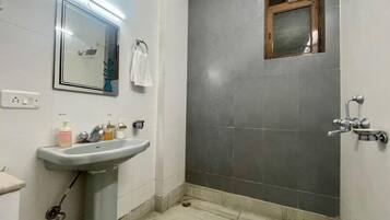 A bathroom with a sink, mirror, and shower area.