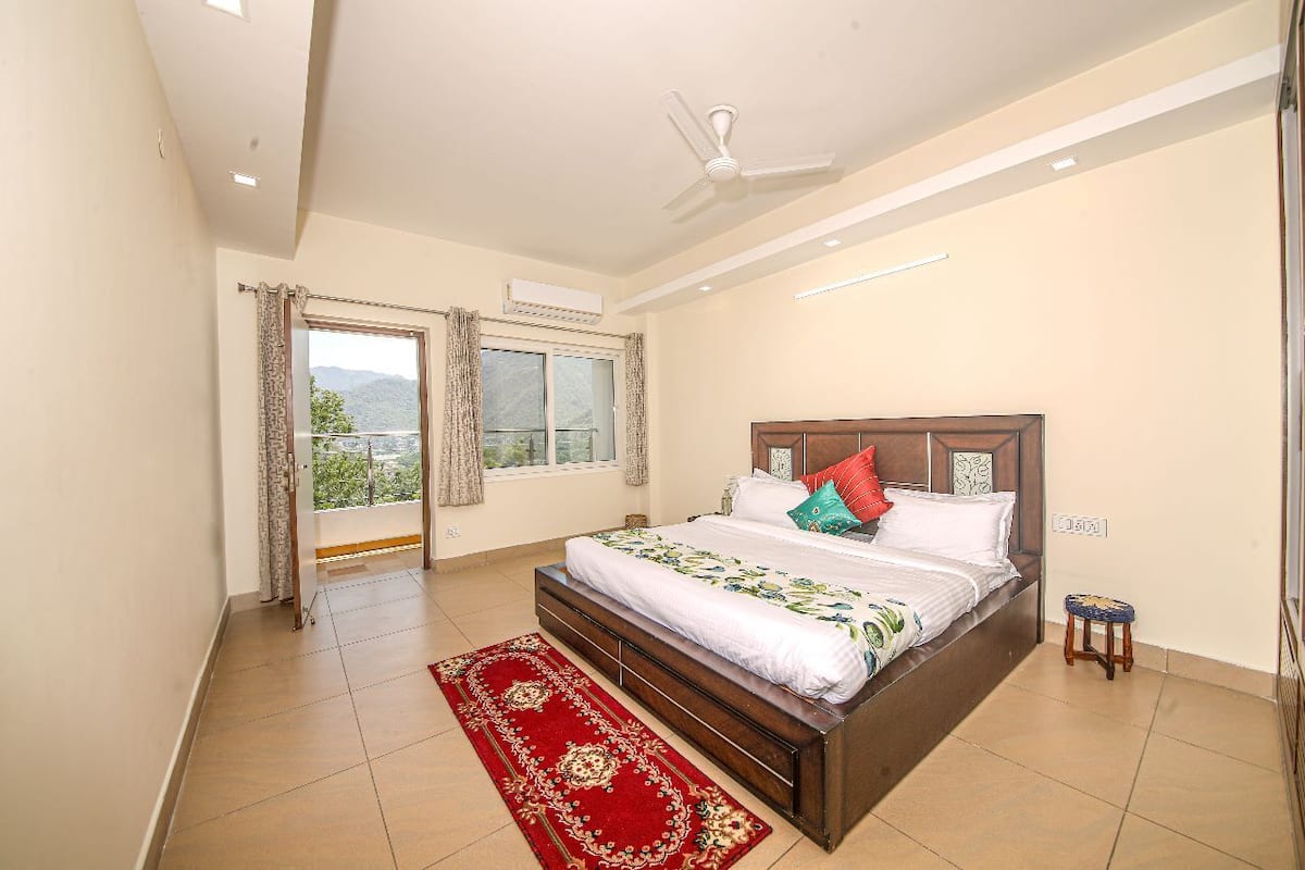 A bedroom with a large bed, a ceiling fan, and a view of the outdoors through a window.