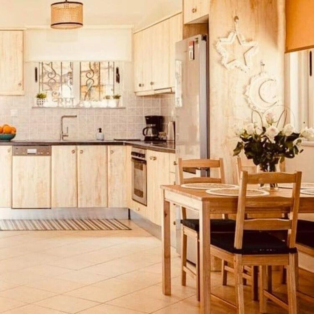 Una cocina moderna con armarios de madera, horno empotrado y comedor con mesa y sillas de madera.