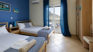 A hotel room with two beds, a balcony, and a view of the sea. - Villa Alysso, fully equipped, modern with shared pool & sea and mountain view (Aptera)