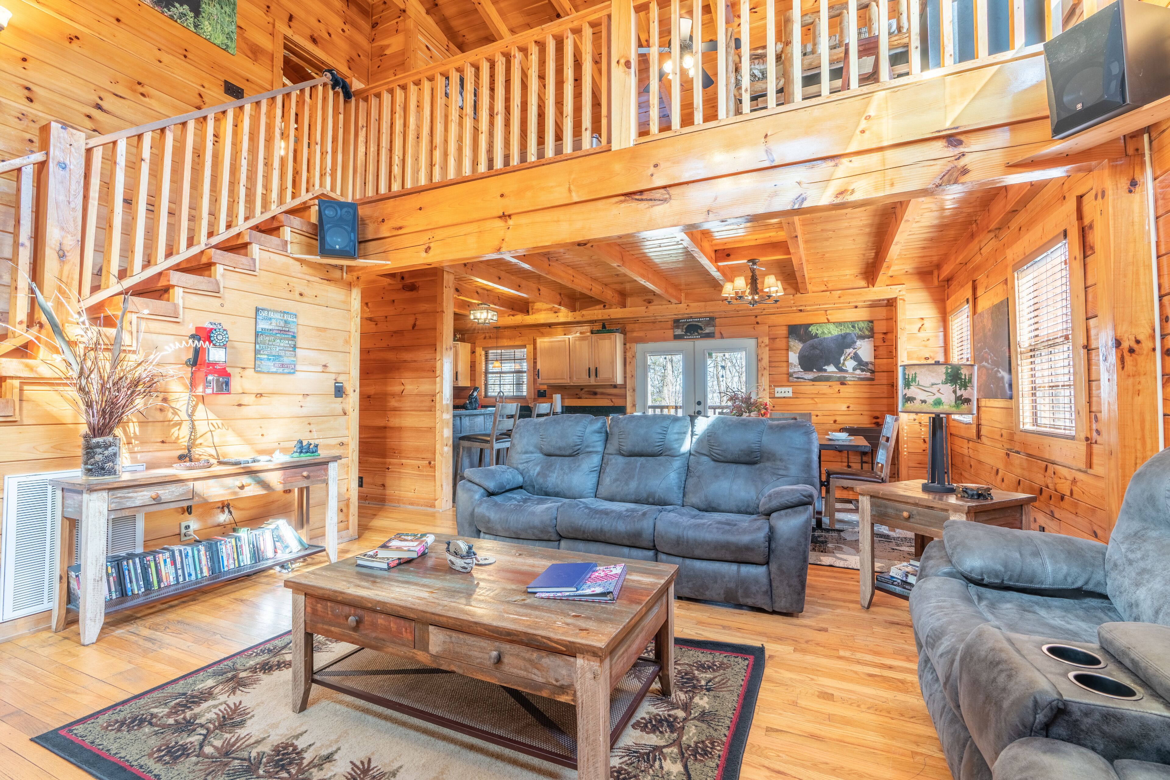 A log cabin interior with a living room, kitchen, and a staircase.