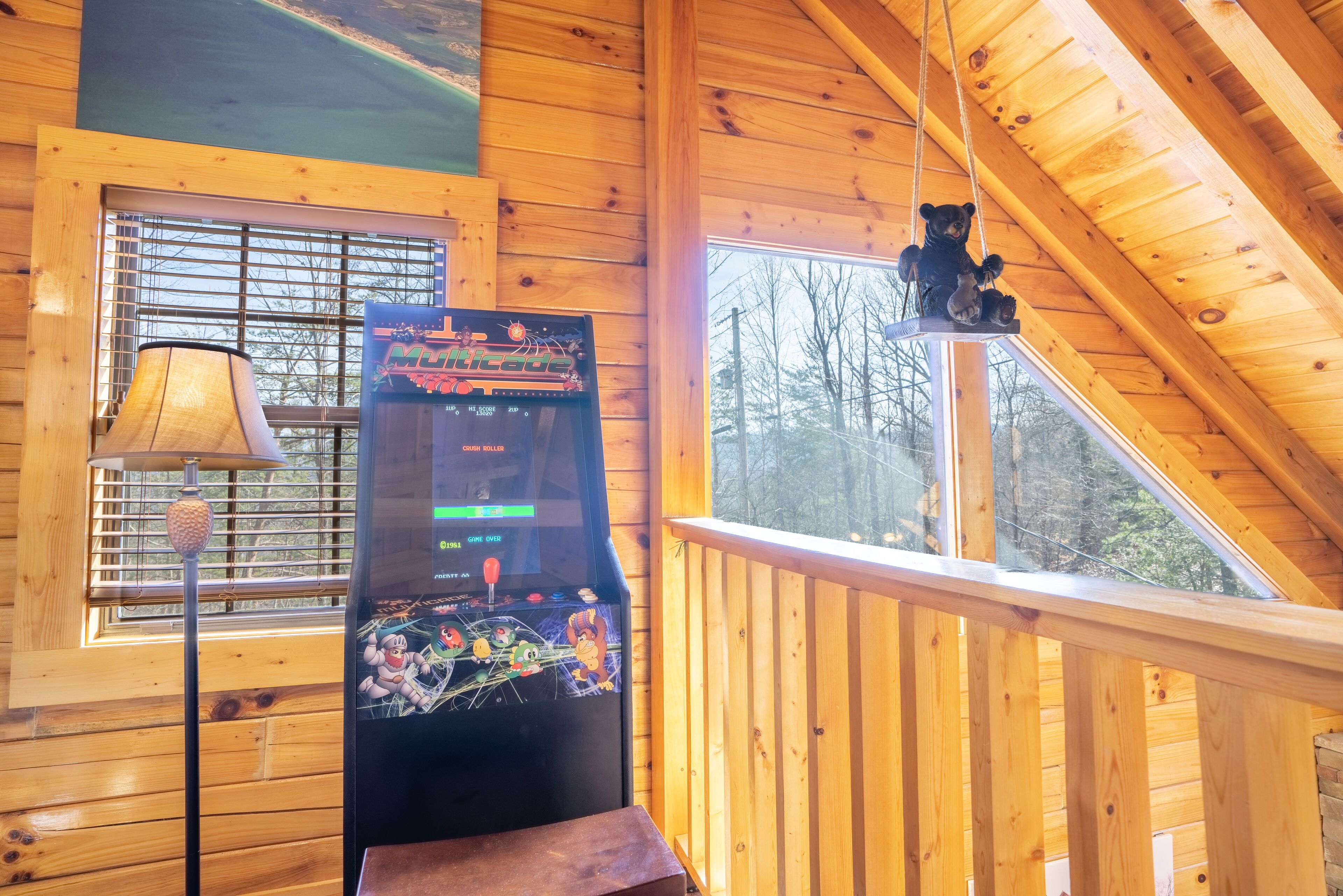 Een houten cabinestijl interieur met een grijpmachine, een lamp en een berenornament op het balkon.