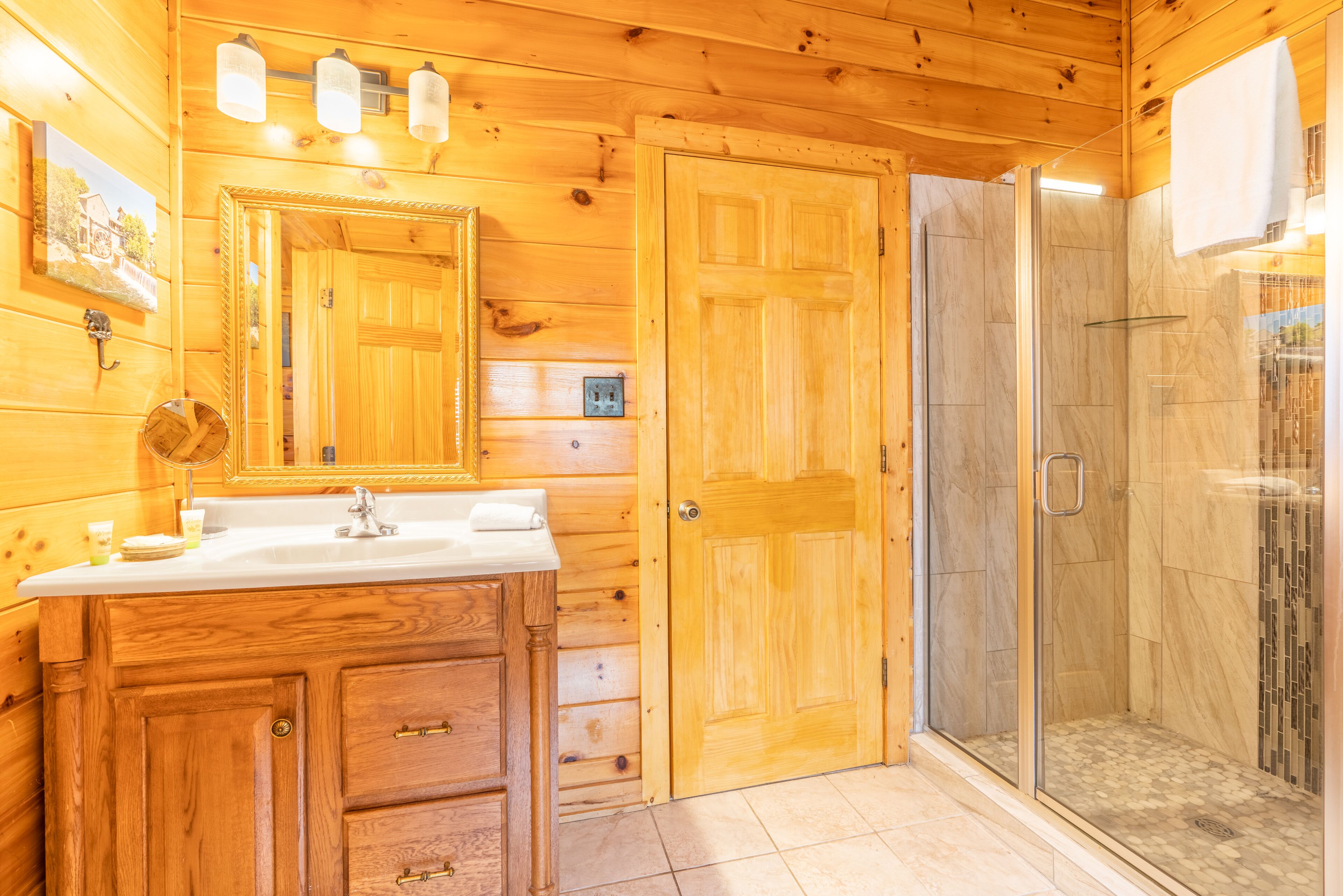 Un bagno in una baita di legno con lavandino, specchio e doccia.